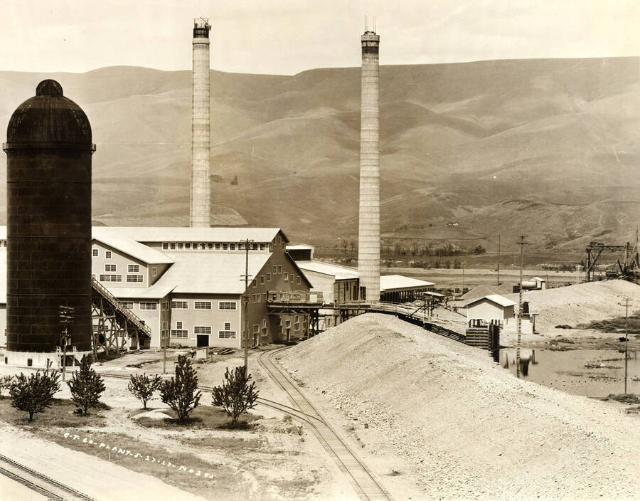 Looking at where the logs enter the mill. Two smokestacks stand behind the entrance. On the right hand side of the picture, the log pond can be seen. Written on the photograph is 'CT CO Plant. 5/27/1927 No. 245.'
