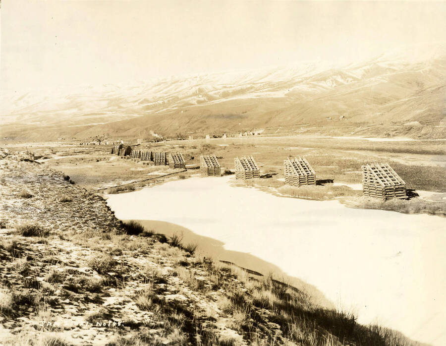 Looking from a distance away, the Lewiston Mill. Log structures stand through the center of the photograph. The description on the back of the photograph reads 'Lewiston Plant in winter'. Written on the photograph is '1/25/1927 No. 188.'
