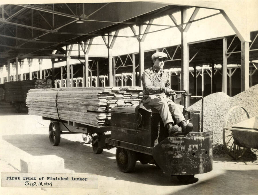 A man drives a load of planks. Attached to the photograph is a description that reads 'first truck of finished lumber. Sept. 15, 1927.'