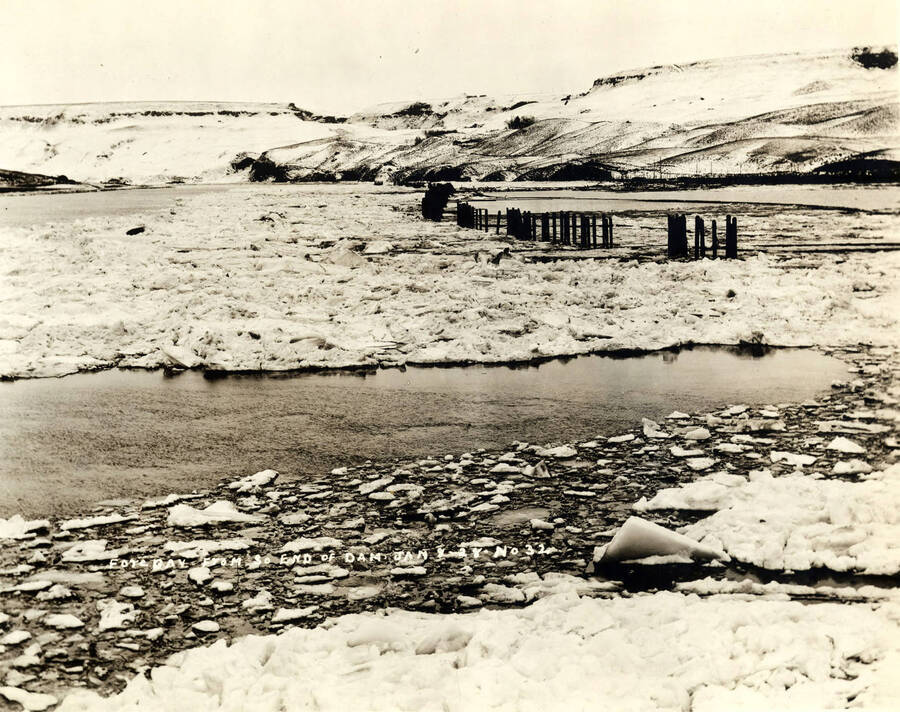 The Lewiston log pond covered in snow and ice. Pilings stick out of the water towards the back of the photo. Written on the photograph 'Fore Bay from South end of Dam, Jan. 8, 1928 - No 32.'