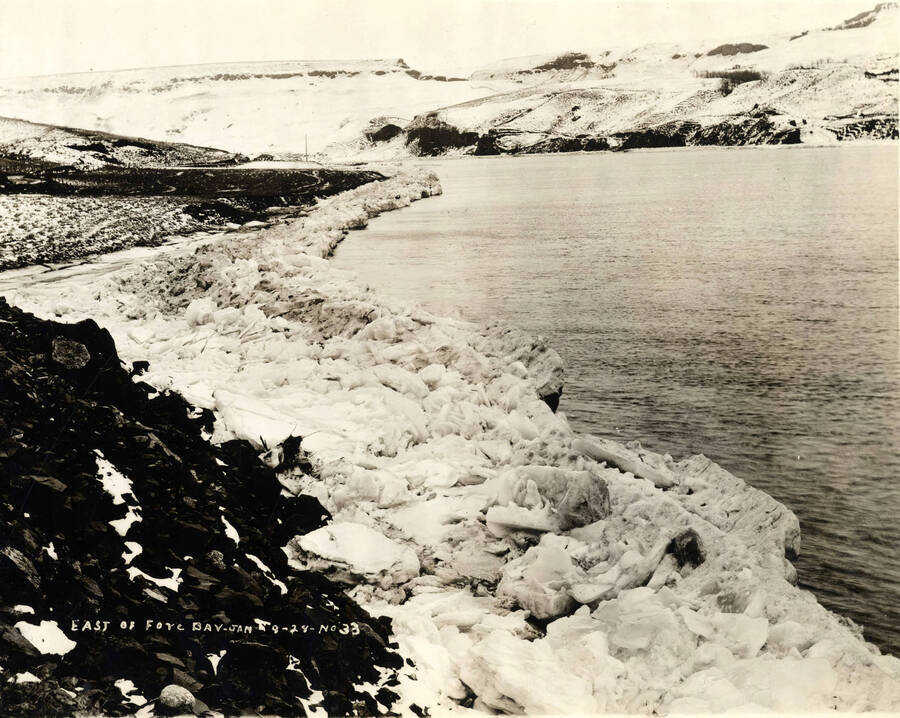 Ice butts up against the bank of the Clearwater river just east of the log pond at the Lewiston Mill. Writing on the photograph says 'East of Fore Bay, January 9, 1928 No. 33.'