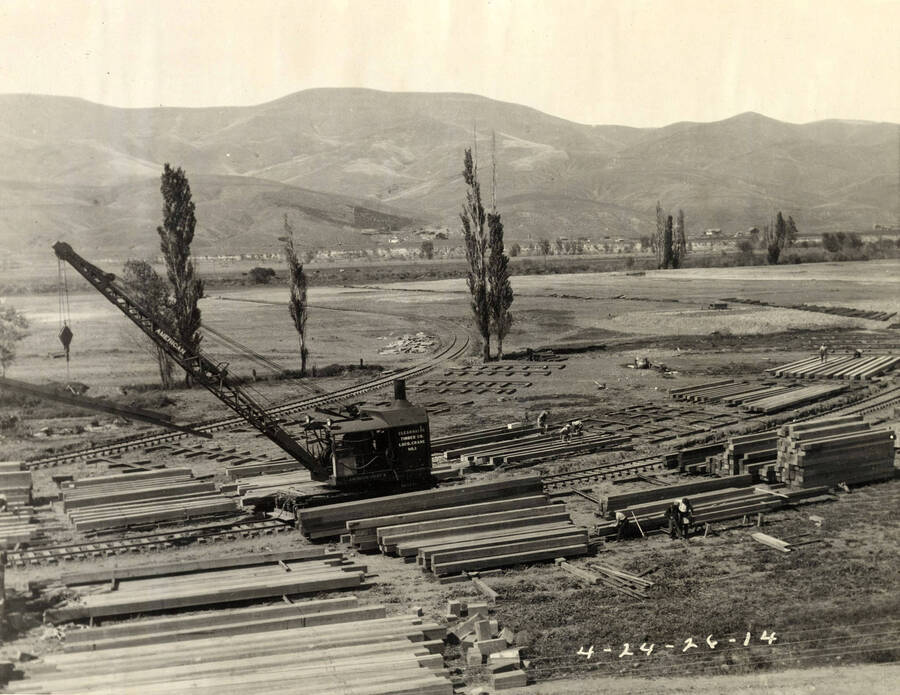 A crane sits surrounded by  piles of lumber. The writing on the side of the crane reads 'Clearwater Timber Co. Loco crane No.1.' Written on the photograph is '4/24/26 No. 14.'