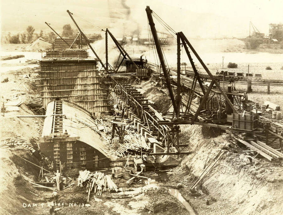 Locomotive cranes are used in the construction of the Lewiston Dam. The description on the back of the photograph says "Clearwater Timber Co. Construction." Written on the photograph is 'Dam 9/16/26 No. 13.'