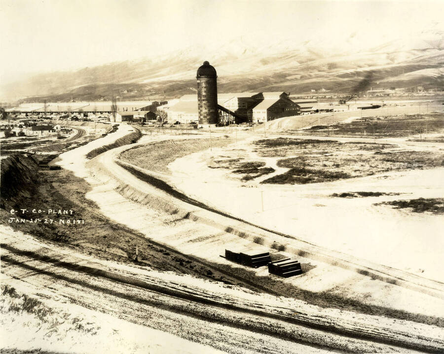 Snow covers the ground surrounding the Lewiston Mill. Where the log pond will eventually be has yet to be filled in.  Written on the photograph is 'CT CO Plant 1/25/1927 No. 181.'