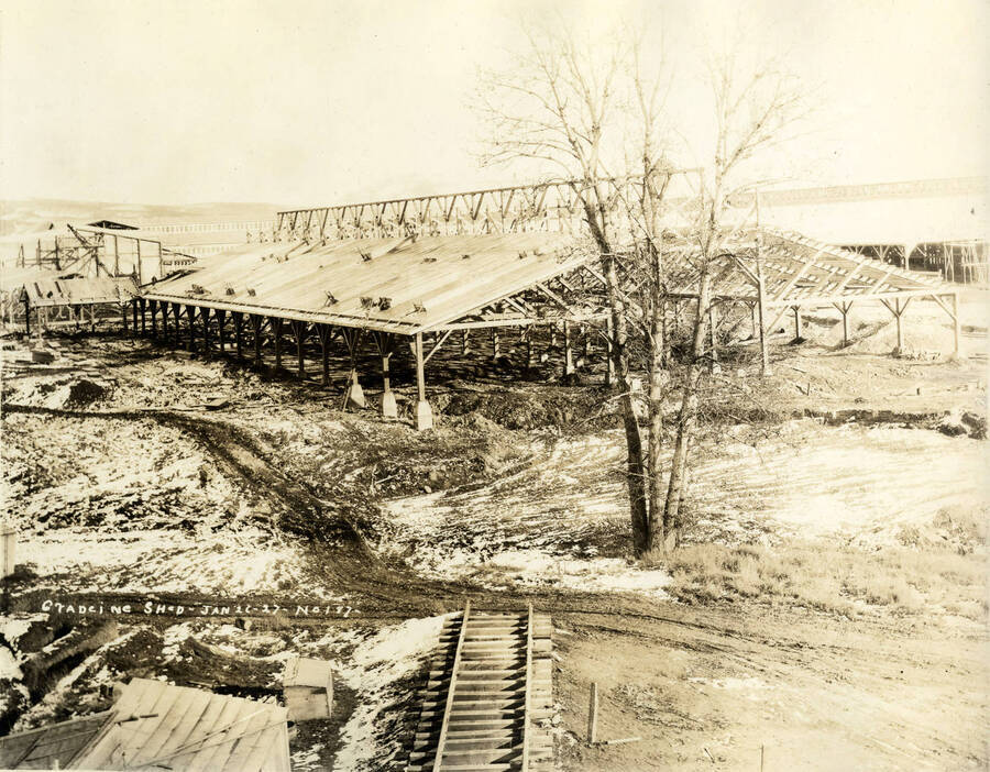 Snow lies on the ground around the partially completed grading shed. At the bottom of the photograph are incomplete railroad tracks. Written on the photograph is 'Grading Shed 1/21/1927 No. 187.'