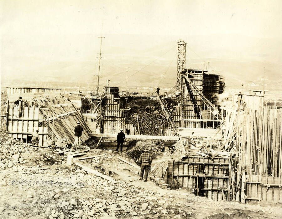 Men standing watching the construction of the Lewiston Mill power plant. Written at the bottom of the photograph is 'Power Plant 11/26/1926 No. 158.'