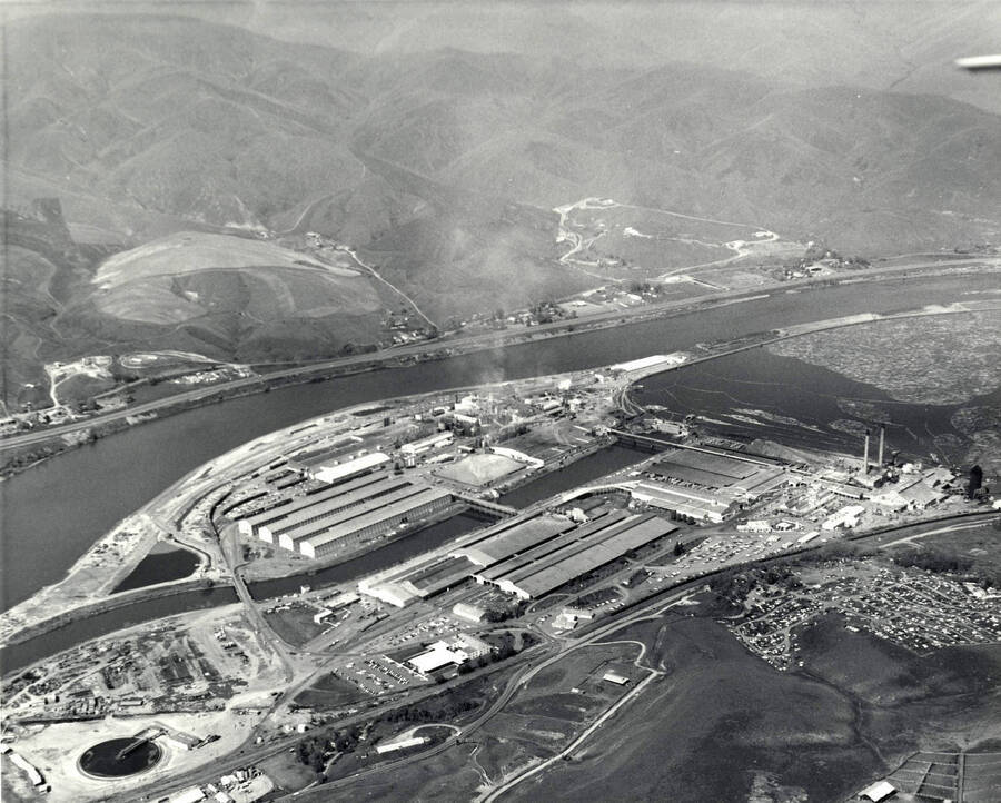 The description on the back of the photograph reads "Aerial view of the Lewiston, Idaho operation of Potlatch Forests, Inc. Included is a sawmill and related lumber operation, wood products specialty operation, veneer and plywood plant, pulp, paperboard and tissue mills, and general offices of the corporation." Photographer is listed as Jack M. Gruber.