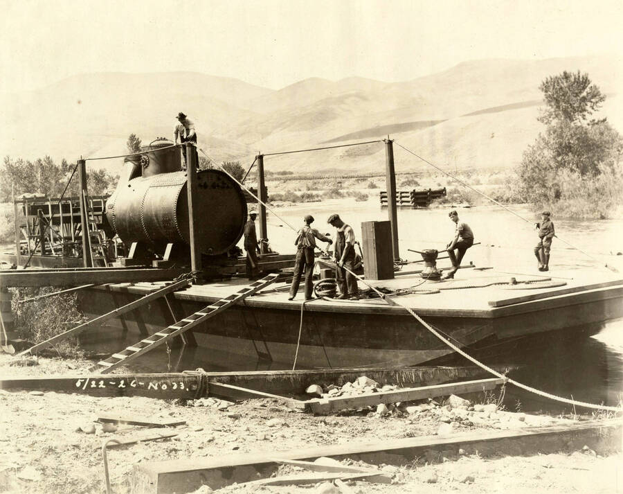 Men work on a barge. In the middle of the barge is a large container. Written on the photograph is '5/22/1926 No. 33'