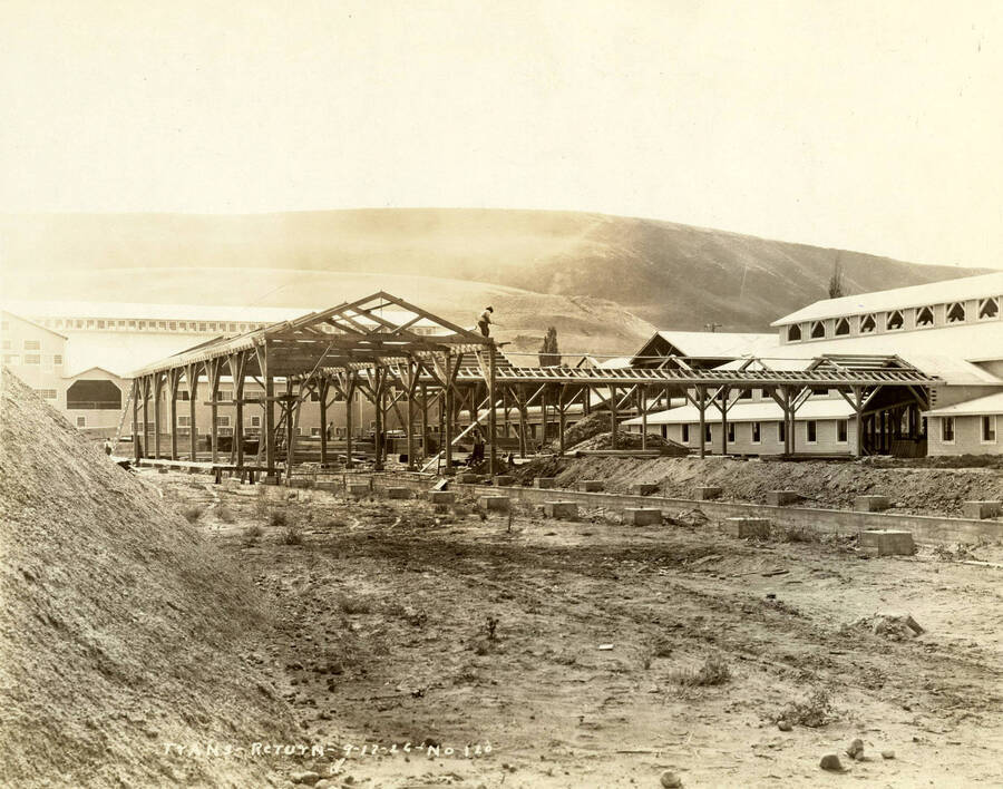 Men work on the framing for buildings at the Lewiston Mill. On the left-hand side of the photograph is completed mill. Written on the photograph is 'Trans-return 9/17/1926 No. 120'