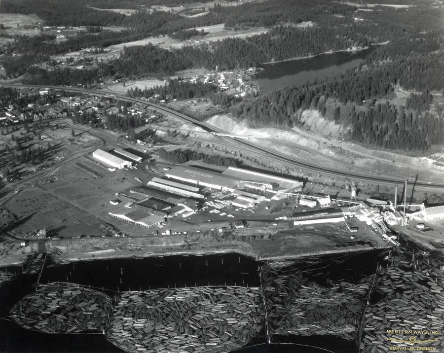 Aerial photograph of the Rutledge Sawmill. In this view, the entire mill can be seen. Above the mill is Interstate 90 and Fernan Lake. Below the Mill are the log ponds. Stamped on the back of the photograph is: 'Western Ways, Inc. Aerial Photographic Specialists  275 Vera Drive Corvallis Oregon, Phone 35266'