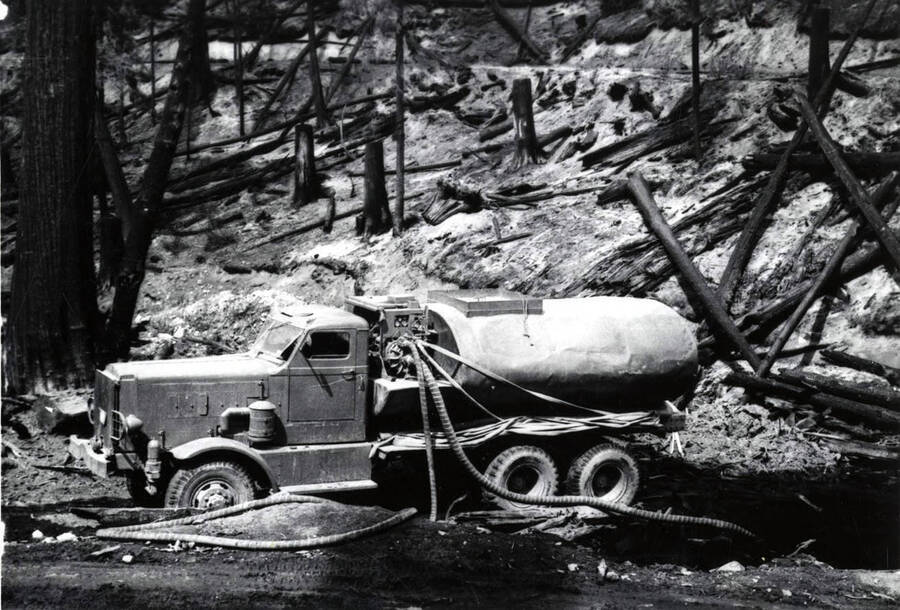 A water tank trunk fills up with water to help fight forest fires. Behind the truck is charred landscape showing where the fire has already been.