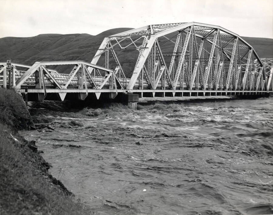 Water rushes US 95 bridge east of Lewiston. The description on the back says "1948 flood  view of water at bridges."