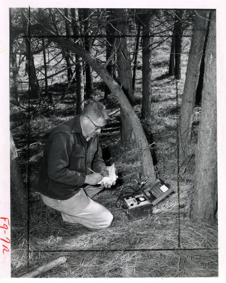 A man writes down numbers from his soil moisture meter (description taken from the back of the photograph)