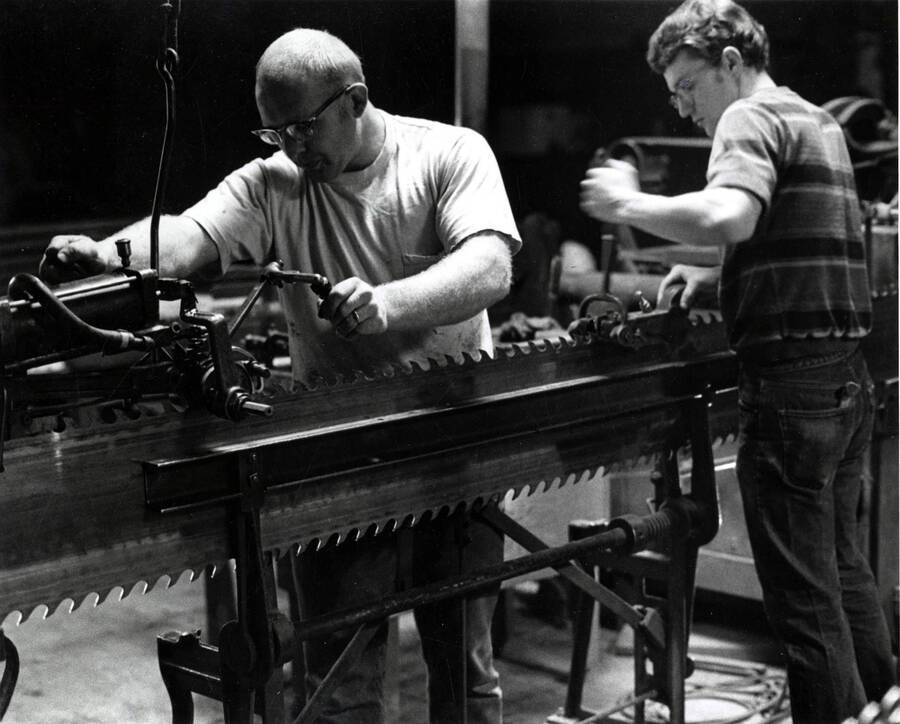 Two men work on a saw in the Clearwater paper mill. On the back, it states that the rights are held by Earl Roberge and American Society Magazine Photographers.