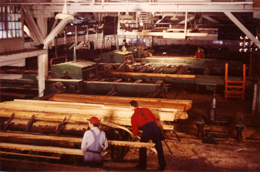 Two men work at taking the planks from the logs and move to the next part of the process.