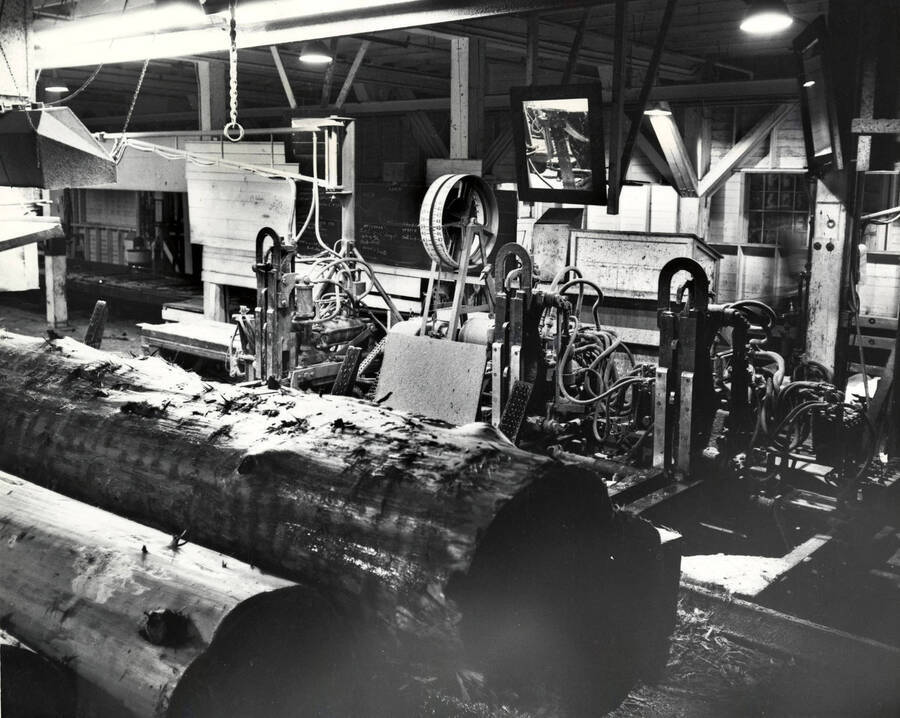 Two logs sit in front a set of machinery. The description on the back reads "Head rig #2 from deck." Also noted on the back is the number #4938-3 as well as the photographer, which reads "Bill Jones Photography 6311 S. W. Wilbard St. Portland 19 Oregon Ch. 4-4943."