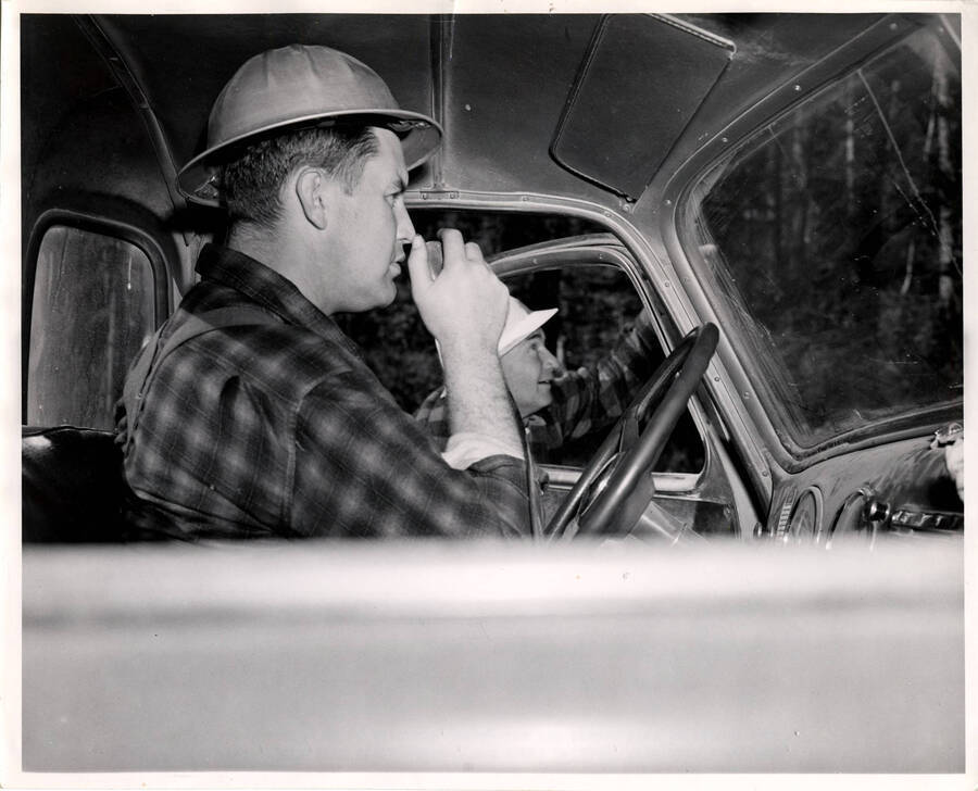 The description on the photograph reads "Bob Tondevold, left, PFI train master, and James Delaney, telephone repairman, call in the location of an aircraft using the WHF transmitter in pickup truck."