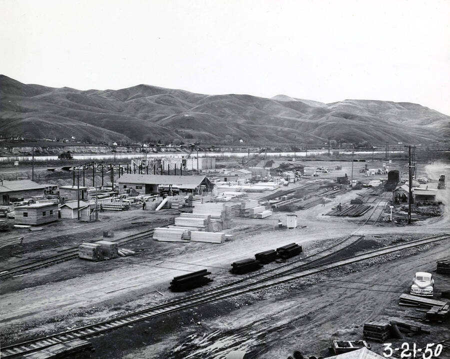 Construction area of the paper mill looking towards the Clearwater river. Railroad tracks are in the foreground while piles of lumber lie waiting to be used.