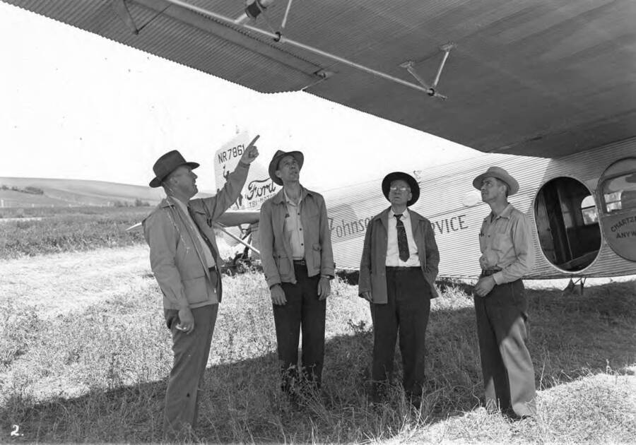 Stanton Ready, State Forester of Idaho, explains the tussock moth spraying equipment installed on the Tri-motor Ford of the Johnson Flying Service to Ed Ring, Assistant State Forester, Thomas Corssley, Special Assistant, and Henry Jones Fire Warden of the Kendrick Forest Protective District.