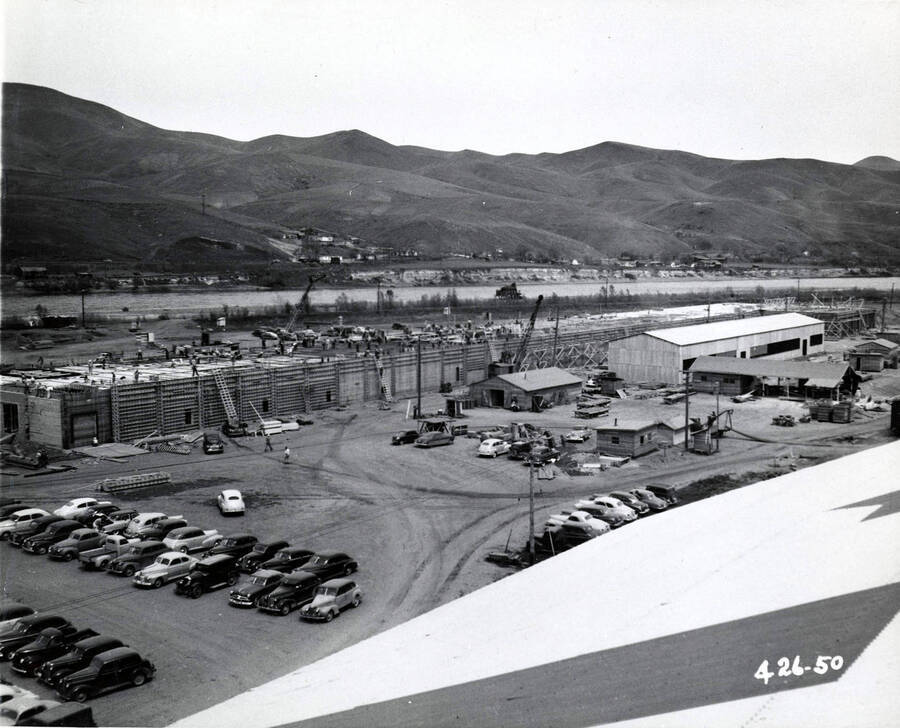 Construction at the Clearwater Paper Mill. One building is being worked on in the back of the photograph, while another is completed in the back right. Automobiles line the parking lot in the foreground.
