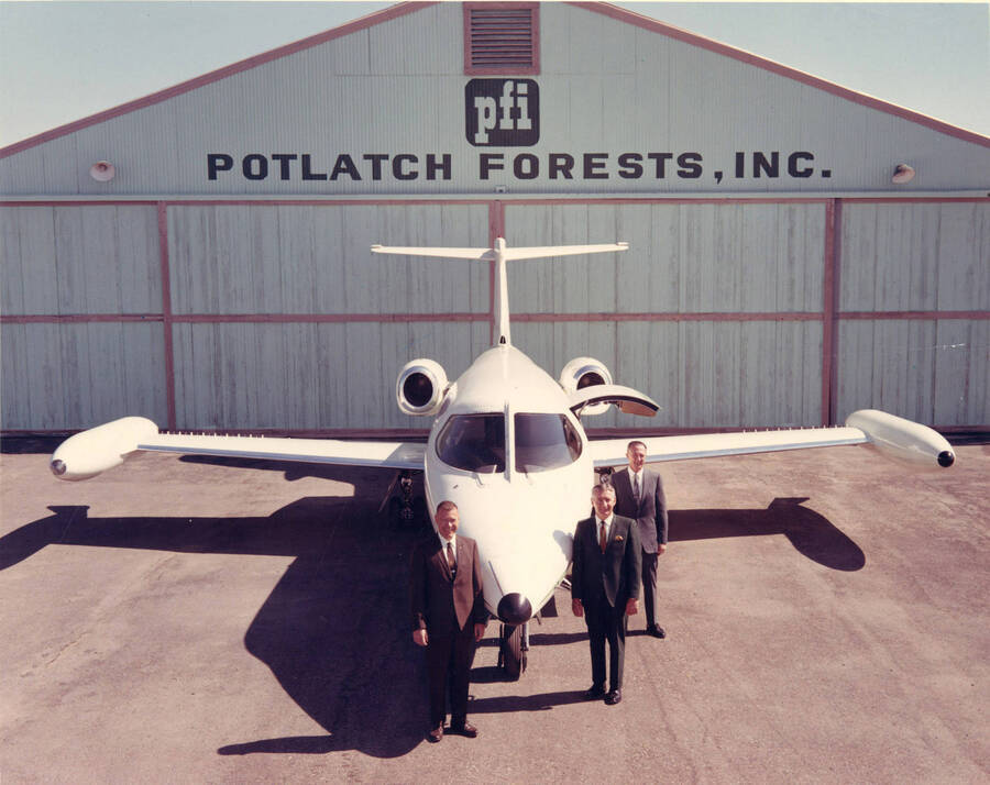 Three new pilots for Potlatch stand in front of the new plane at a hanger at the Lewiston Airport. A. Brandt stands on the far right near the wing. This new plane is a Lear Jet with the tail number N256P.