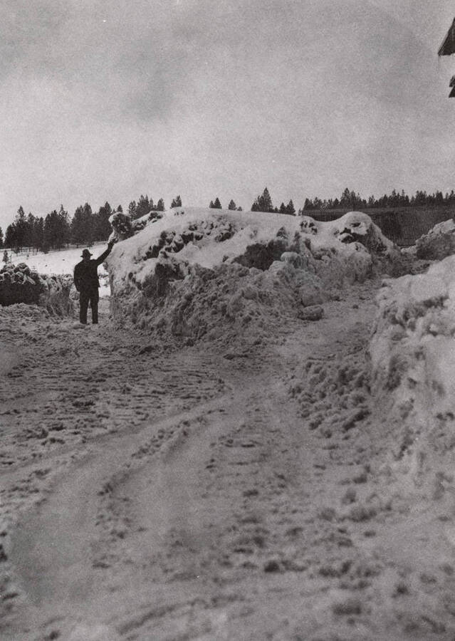 Man standing beside a large pile of snow