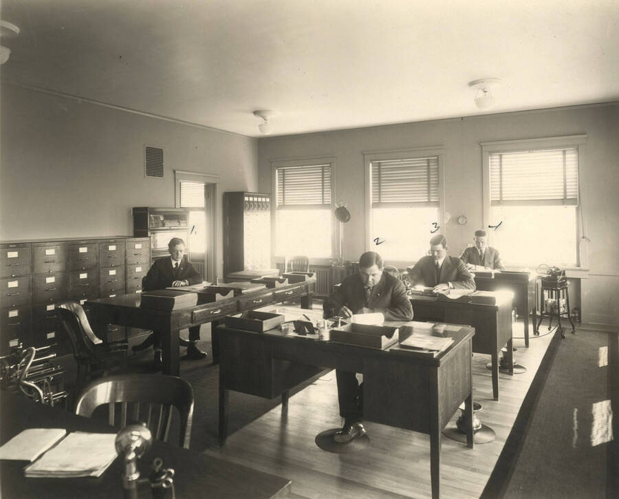 Men at their desk in the Sales Dept.  Note the old Dictaphones.