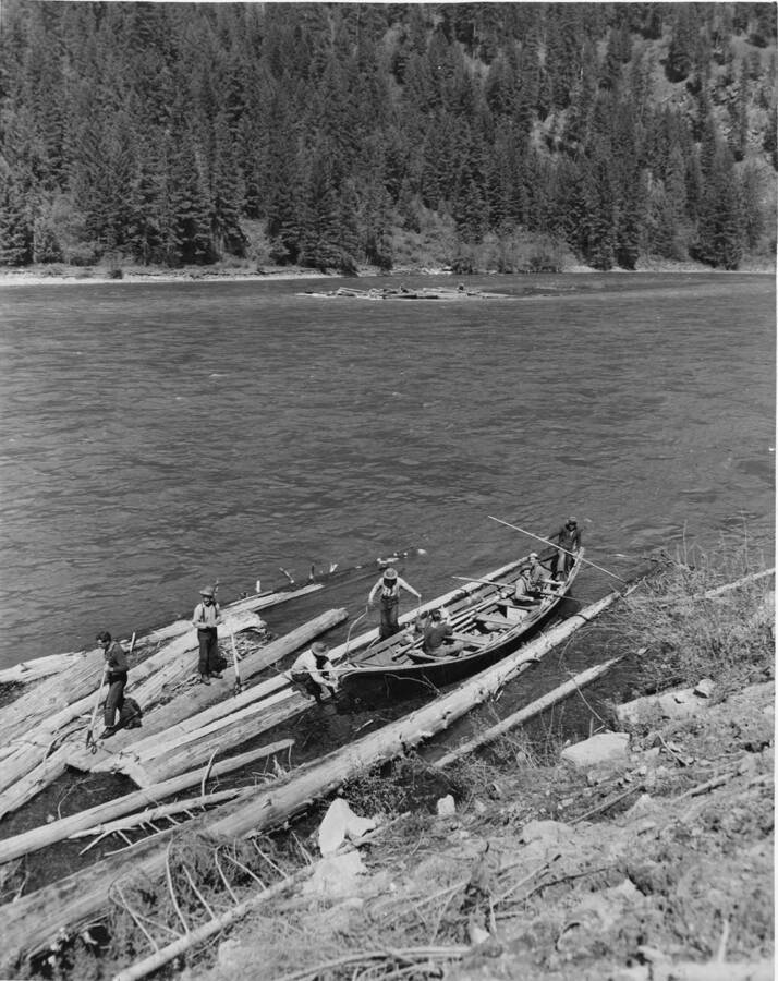 The bateau crew moves logs that have become stuck on the shoreline back into the middle of the river.