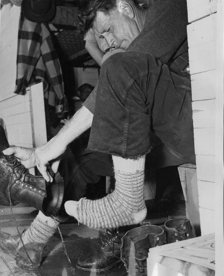 A logger removes his boot and pours out the water from a day's work.