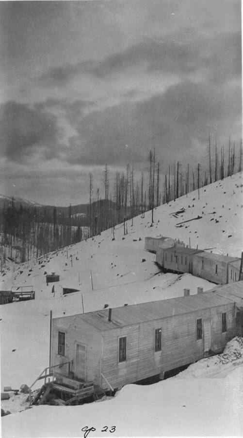 The bunkhouses of Camp 23 on a ridge. Description on the back says 'Cp 23 in 1924 (no RR didn't get to Hdqtrs until 1927 must be 1934).'
