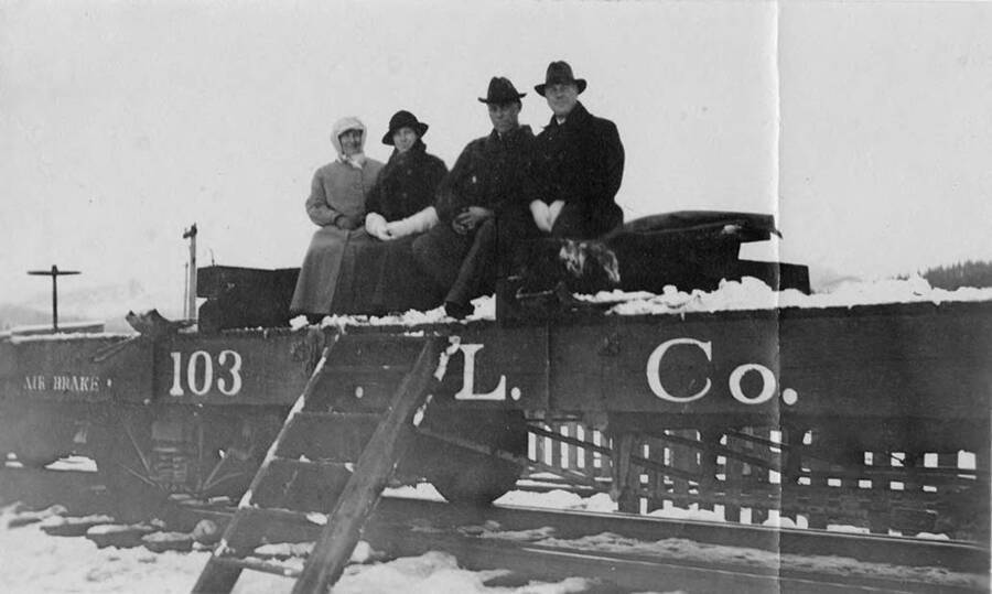 John, Noeher (?), Ms. Bloom, and Mary See Rockwell sit on a flatcar covered in snow.
