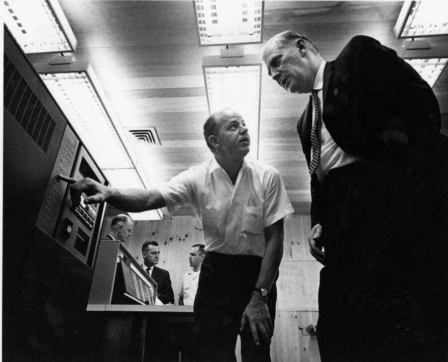 Caption reads: 'Potlatch Forests, Inc., officials inspect their IBM 1710 process control system, first of its kind in the nation, immediately after it has been installed on paper machine number one at the company's Lewiston, Idaho, mill. In the foreground are Dwain M. Bates, instrumentation engineer; and V. V. Vallandigham, vice president for pulp, paper and converting. In the background are from left Edwin C. Rettig, executive vice president and general manager; Donald Keller, production manager, and Robert Zipse, computer systems programmer.'