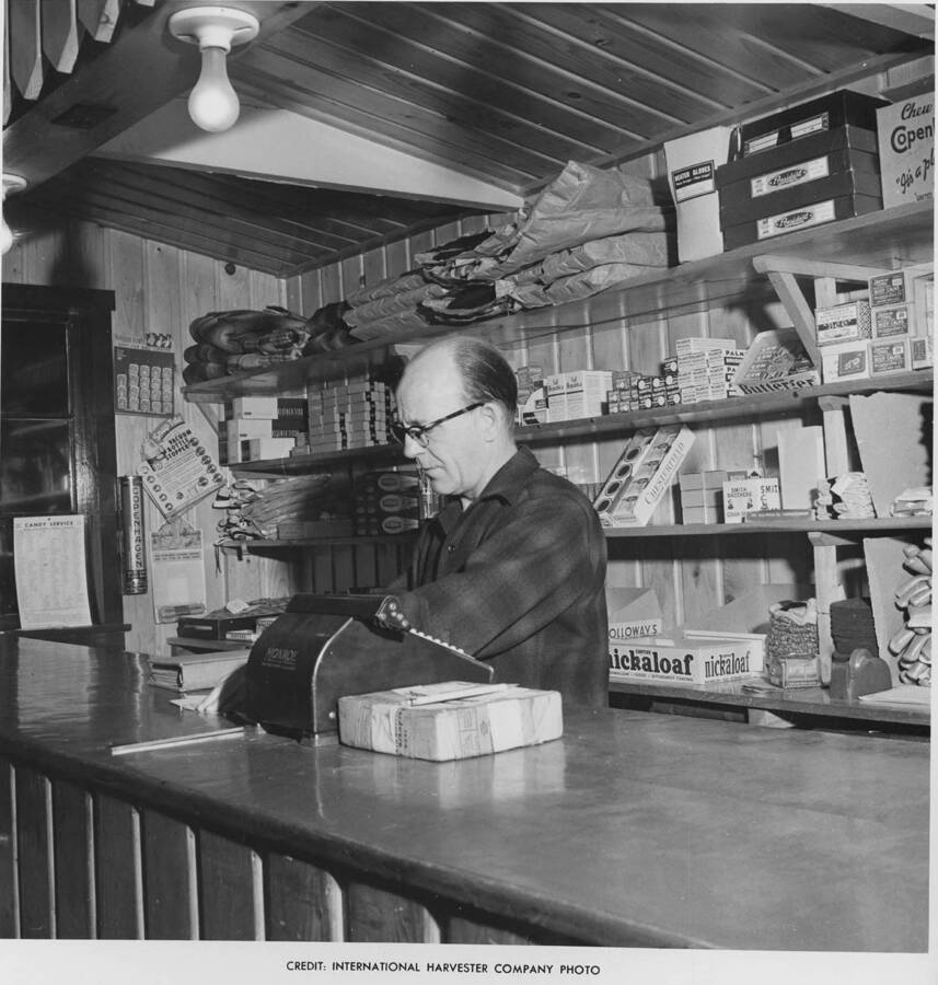 Jack Anderson stands next to the cast register at the Camp 44 store. He was the camp clerk. Behind him are stores of goods that lumberjacks might need.