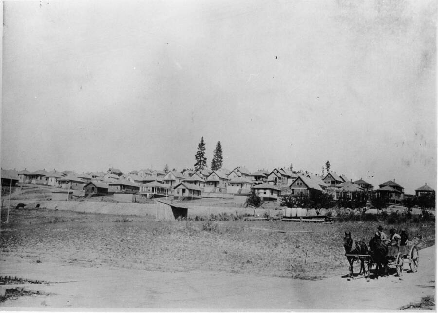 The view of the residence hill in Potlatch, Idaho. In the lower right hand corner, two horses pull a wagon with three men.