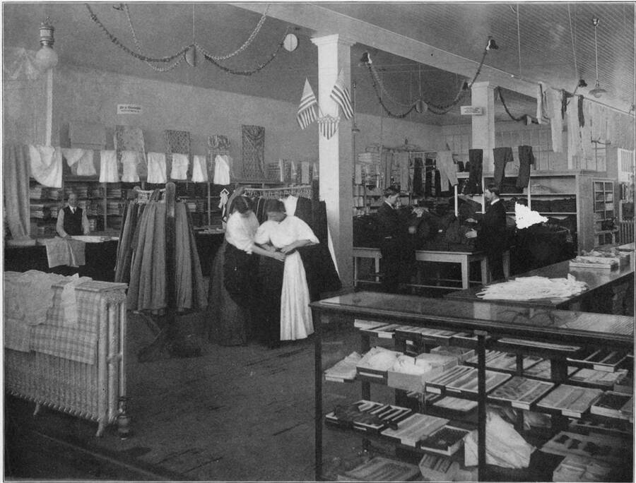 The dry goods and clothing department in the Potlatch Merchntile Company store. Scanned from the book 'Potlatch Lumber Company: Manufacturers of Fine Lumber'. The back cover says 'Photographed and published by F. D. Straffin, 336 Riverside Ave. Spokane Wash. Printed by Inland Printing Co. Spokane, Wash'.