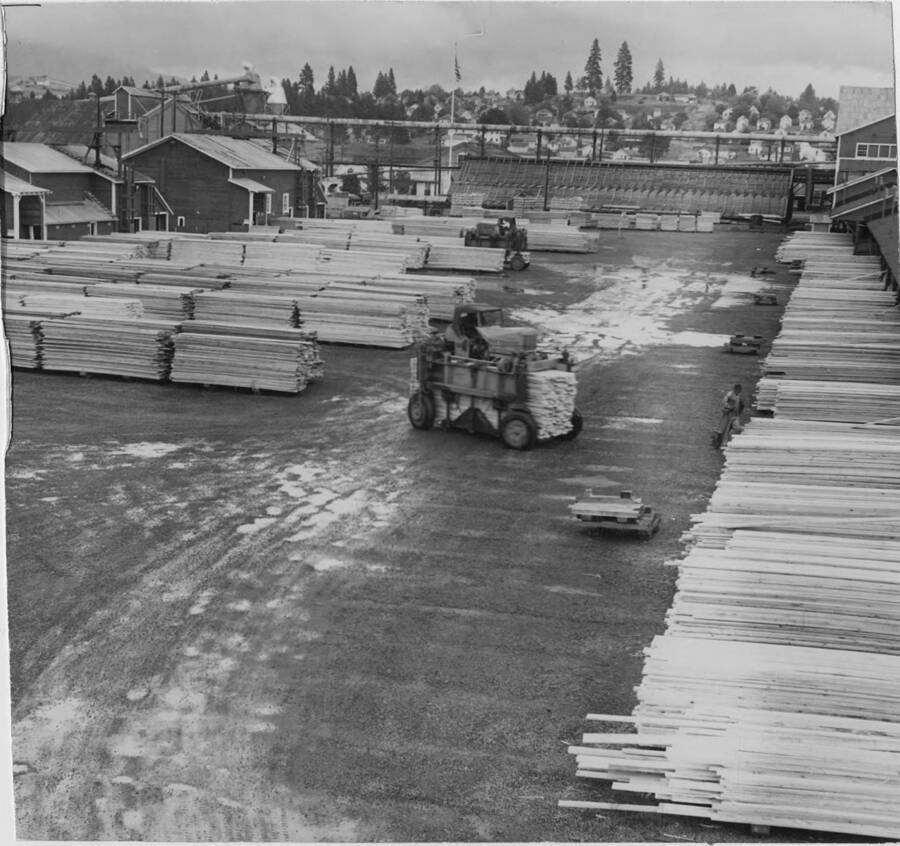 The lumber yard at the mill in Potlatch, Idaho. Two tractors work to move lumber places.