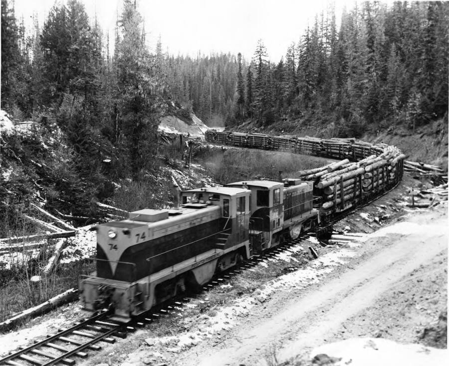 Two PFI diesel-electric engines moves a string of loaded flatcars over company tracks near Headquarters, Idaho. The cars will be taken from Headquarters to Lewiston, Idaho on a branch line of the Camas Prairie R. R.