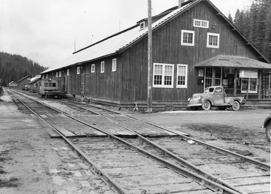 The railroad buildings in Headquarters, Idaho. A pickup truck is parked in front of the one of the buildings.