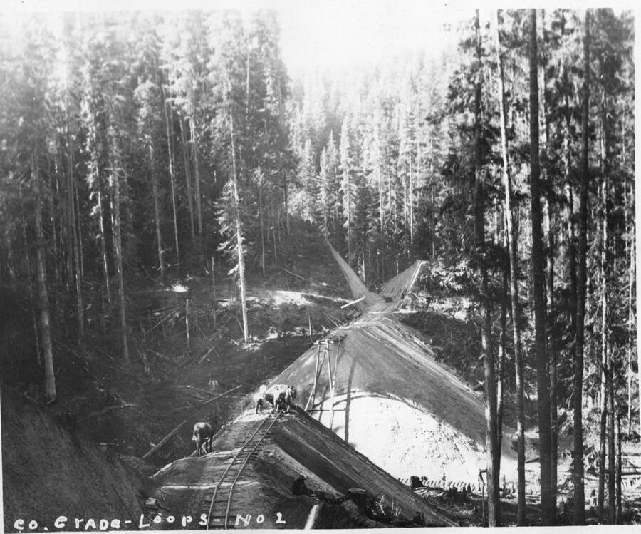 Men work on the railroad bridge going over a logging run.