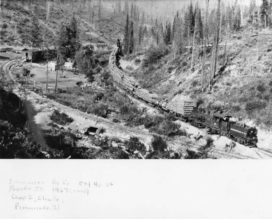 Engine #22 from the Intermountain Railroad Company pulls flatcars full of logs near Camp 2 in the Nez Perce National Forest. Written on the photograph: 'Intermountain Ry Co. Eng No 22. Payette, ID 1927 (circa) Camp 2. Clear Fl, Pioneersville, ID.'