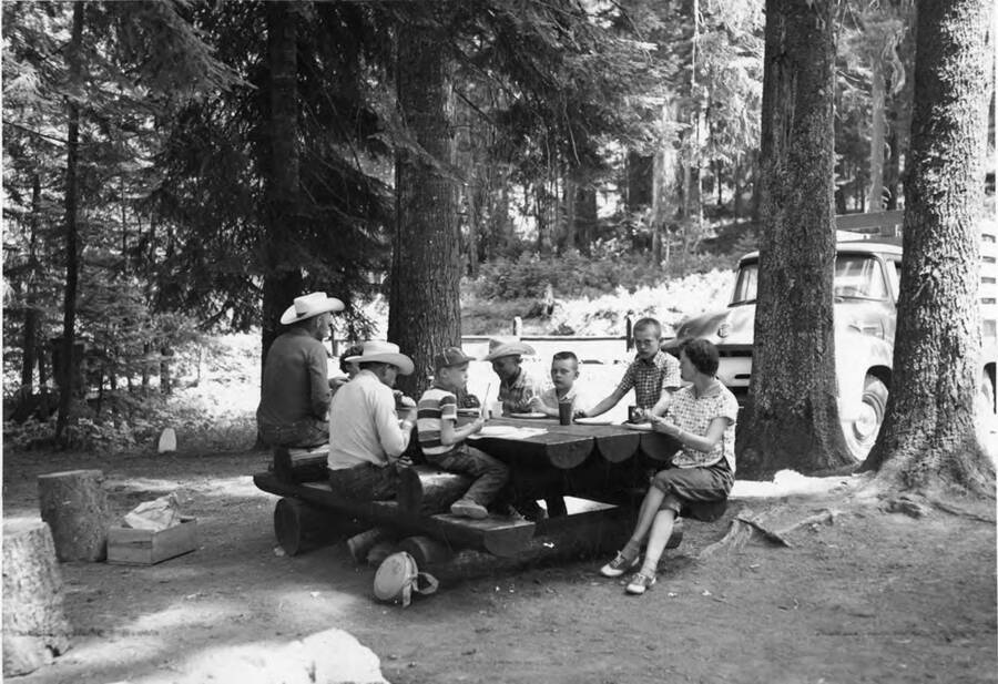 A family group enjoys a picnic lunch at the Fohl picnic area on state highway 11 between Pierce and Weippe. It also says on the back of the photograph that 'plans are to move this PFI facility to a new location because of heavy public use and lack of room to expand at the present site.'