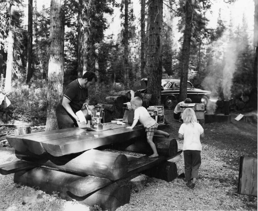 A family group enjoys an outing to the Hollywood Campground on Idaho Highway 11 between Pierce and Headquarters. The area, developed and maintained by Potlatch Forests, Inc. was expanded and improved last year as part of the forest products company's community relations program. It is one of the nine outdoor recreation areas made available in North Central Idaho by Potlatch for public use.
