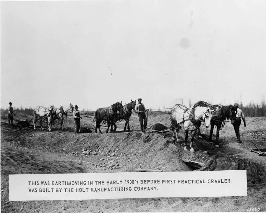 Several teams of horses move earth in a building project. On the photograph is a sign that reads 'this was earthmoving in the early 1900's before first practical crawler was building by the Holt Manufacturing company.'