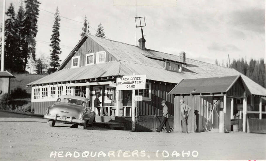 The Post Office of Headquarters, Idaho is pictured. In front of the Post Office is a car.