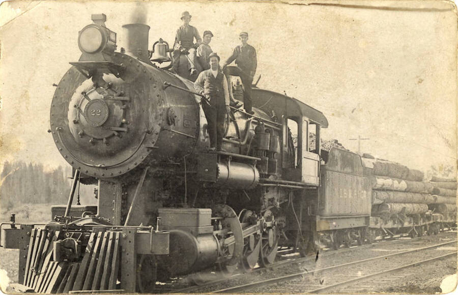 Four men posed on the engine of a logging train.