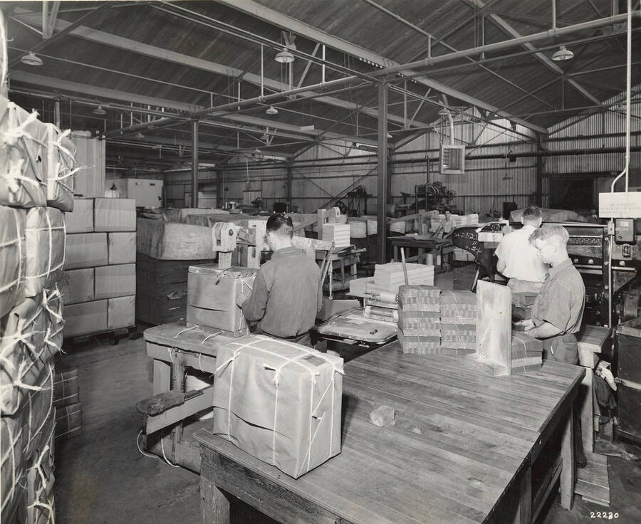Men work to finish paper products and tie them into bundles for transport.