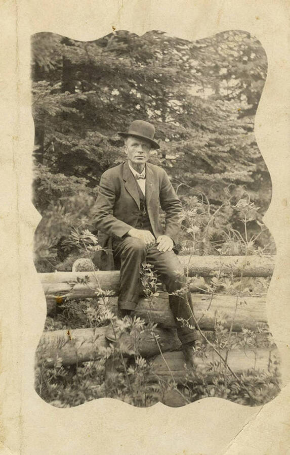 A postcard showing a man wearing a bowler hat sitting on a fence. On the back, it is written 'Fakealoo Brown. Assistant super.'