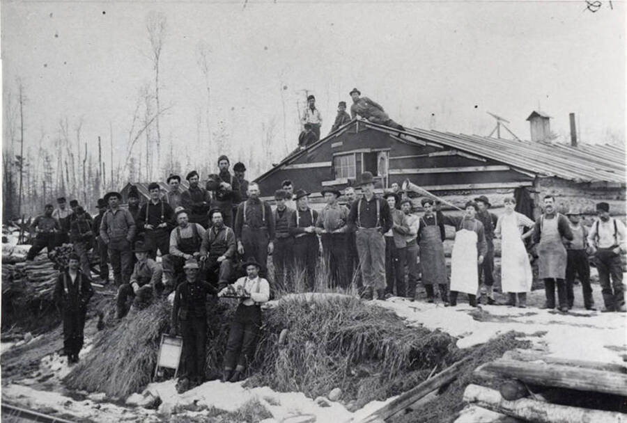 The description on the back of the photograph sais 'from logging Camp 5 (Bovill)' and the photograph is stamped on the front with July 1965. However, the clothes of the men in the photograph are older than that.