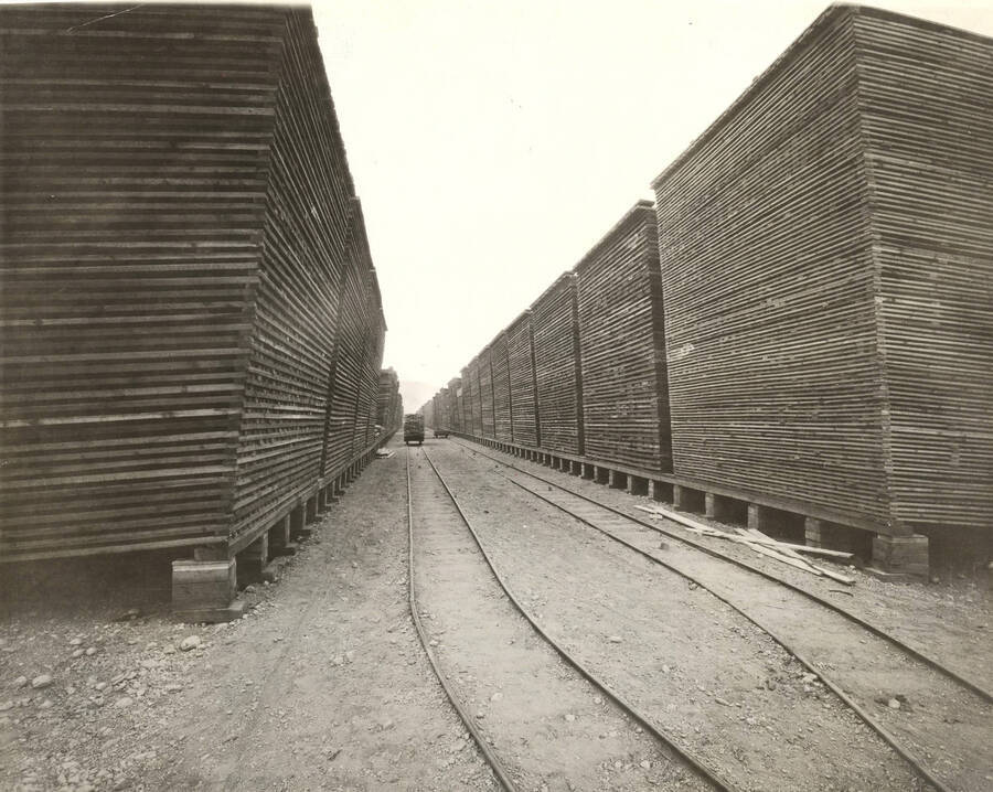 View of lumber yard.  Note railway tracks running between stacked lumber.