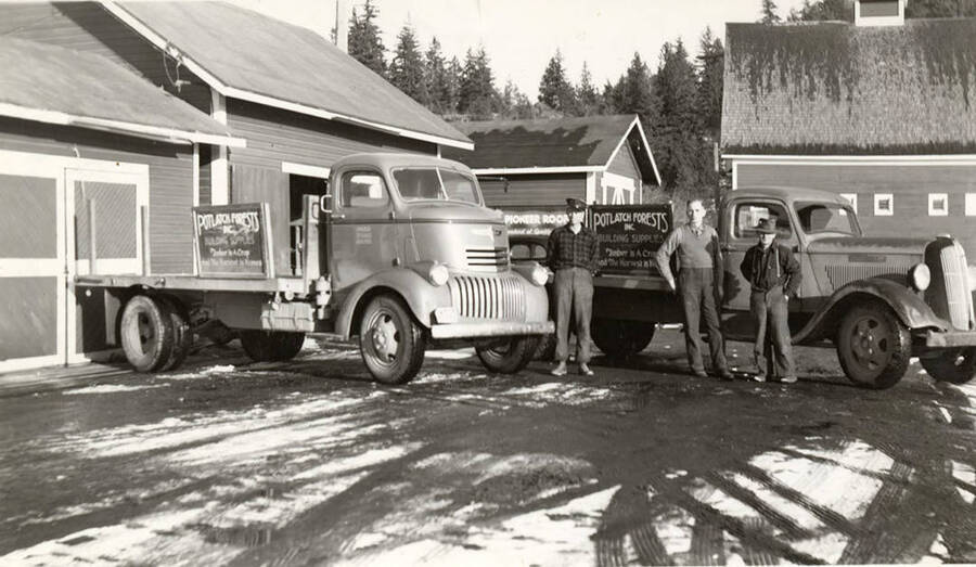 Ray Bjormstad, Clyde Durdy, and George Alexander stand in front of two trucks bearing signs for the Potlatch Company.